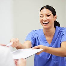 a dental team member handing a patient forms