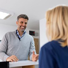 Happy patient talking with dental team member at front desk