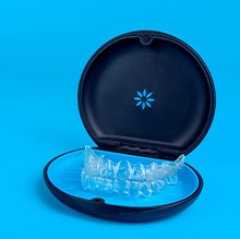 A single set of Invisalign trays in the carrier case with a light blue background