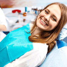 Woman at dentist’s office smiling after root canal therapy in Virginia Beach, VA